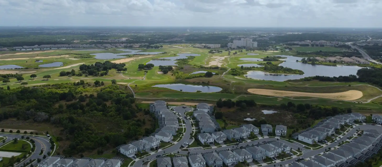 Aerial view of tile roofed homes, a golf course and lakes in inland Central Florida near Four Corners