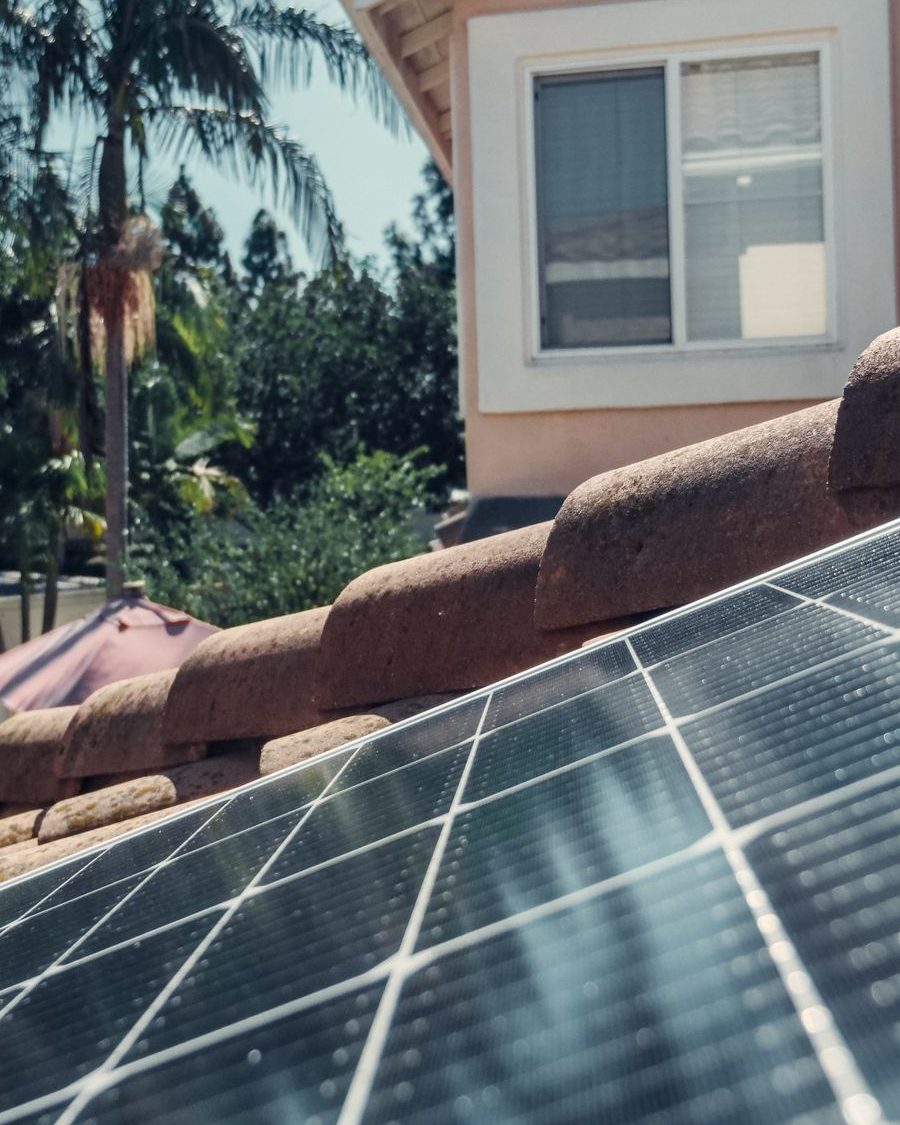 Rooftop solar panels on a tile roof home with palm trees